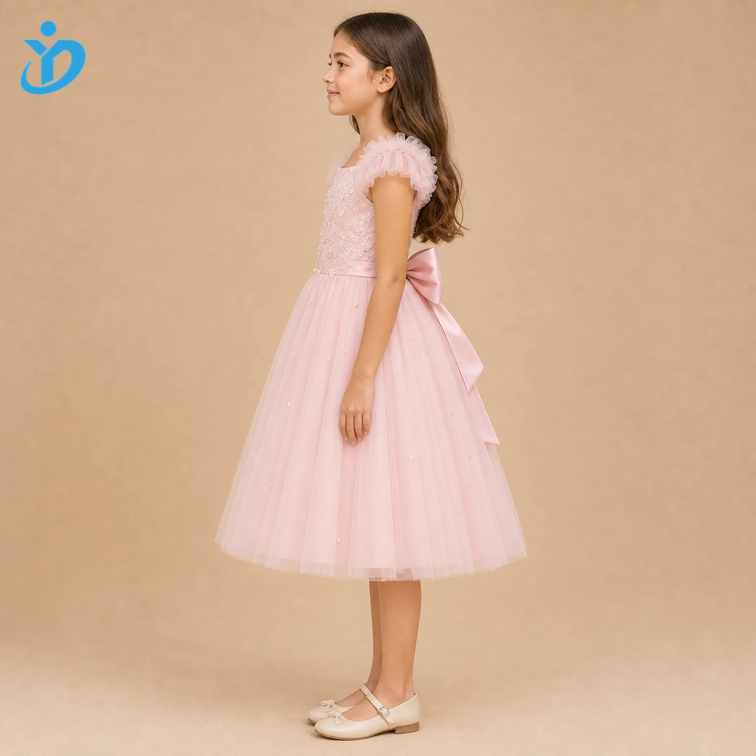 Full body side view of custom girls tulle princess dress showing pink layered tulle, satin lining, large bow, embroidered bodice, pearl and sequin decoration and Dongguan Yidi Clothing Co Ltd transparent logo