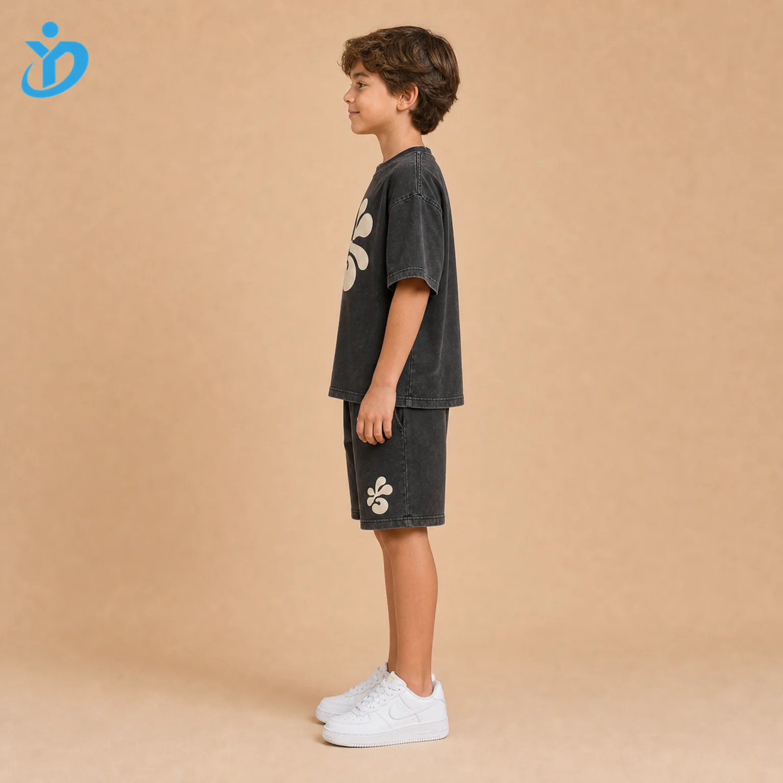 Custom kids 3D puff print T-shirt and shorts set side view with washed charcoal black streetwear fabric, raised cream puff print and Dongguan Yidi Clothing Co Ltd transparent logo.