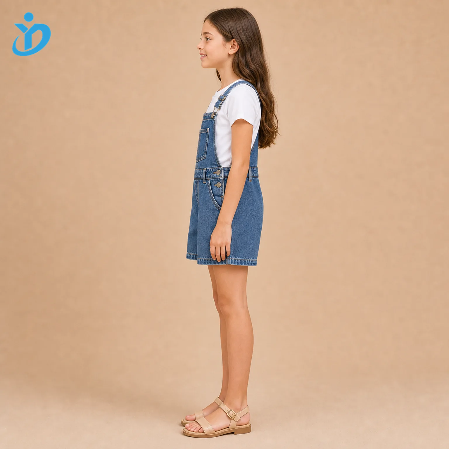 Full body side view of custom kids denim overall romper showing washed denim, adjustable strap metal buckle, side metal buttons, double topstitching, white T-shirt styling and Dongguan Yidi Clothing Co Ltd transparent logo