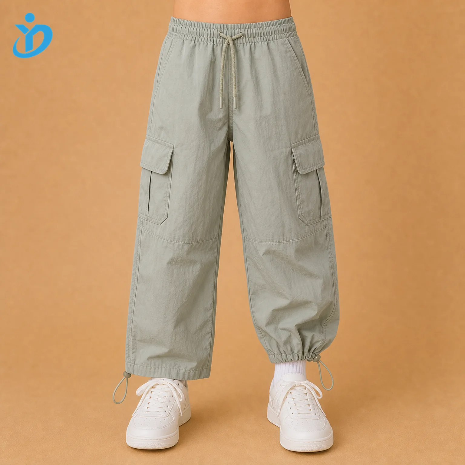 Lower body front view of custom kids lightweight parachute cargo pants with loose silhouette, adjustable elastic waist, side cargo pockets, adjustable hem cord and Dongguan Yidi Clothing Co Ltd transparent logo