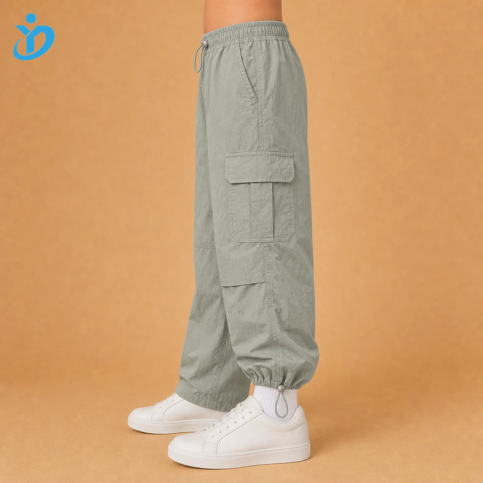 Lower body side view of custom kids lightweight parachute cargo pants showing side cargo pocket, parachute nylon fabric, adjustable waist and cinch hem with Dongguan Yidi Clothing Co Ltd transparent logo