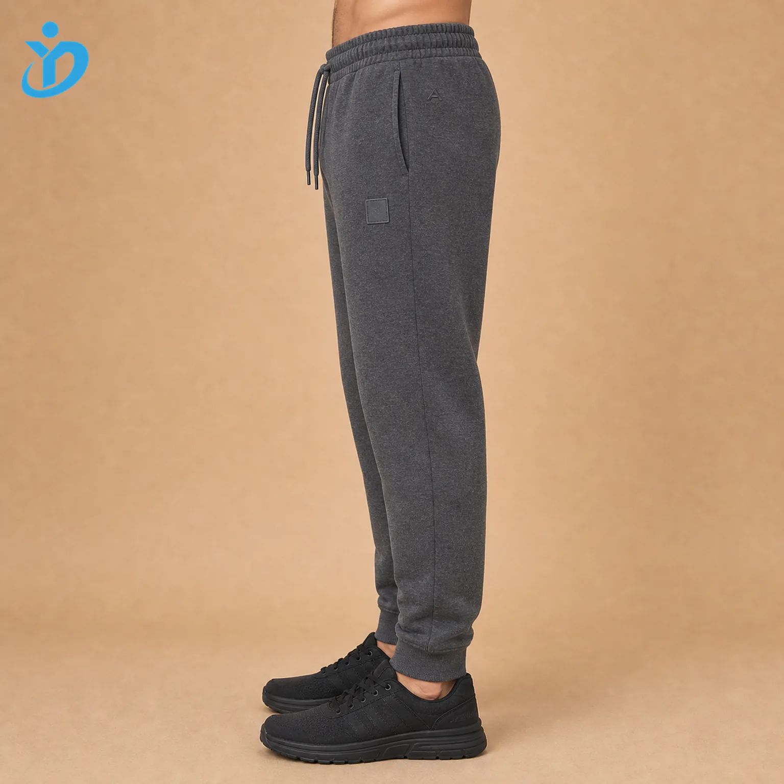 Lower body side view of custom mens French Terry fleece jogger pants showing tapered fit side pocket rib cuff elastic waistband drawcord silicone logo patch embroidery and Dongguan Yidi Clothing Co Ltd transparent logo